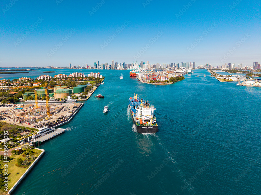 Obraz premium Miami, Florida, USA - March 20, 2025: Miami port. Container ship. Cargo Warnow Whale Limassol ship with container in Miami aerial. Freight container on cargo vessel. Cargo ship vessel. aerial view