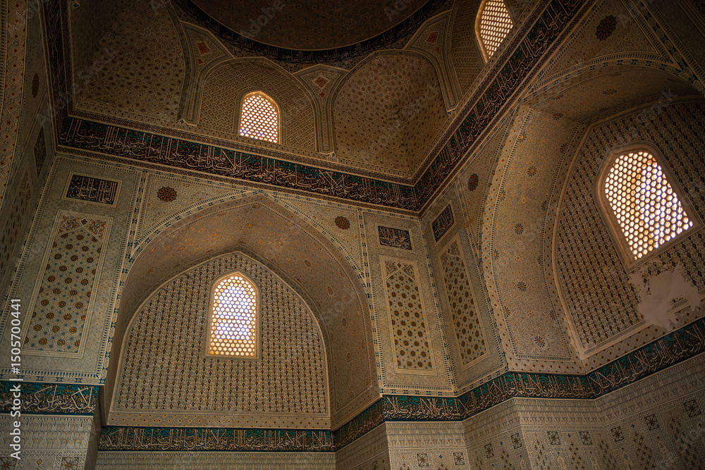 Naklejka premium Interior of Gur e Amir mausoleum in Samarkand with intricate Islamic patterns, gold details, arabesque mosaic, decorative arches, calligraphy illuminated by sunlight through lattice windows