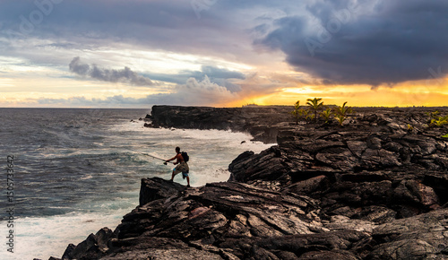 Silhouette of a man fishing off rocks during sunset on Big Island of Hawaii