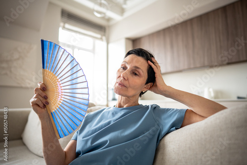Photography Exhausted mature woman fanning herself at home due to unbearable heat