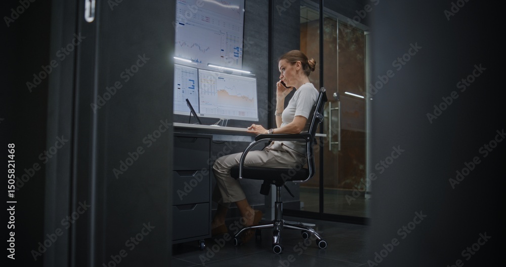 Female Financial Analyst Having Phone Call, Analyzing Real-Time Stocks, Exchange Market Charts on Multi-Monitor Computer and Digital Tablet. Businesswoman Working in Financial Agency Office at Night. Female Financial Analyst Having Phone Call, Analyzing Real-Time Stocks, Exchange Market Charts on Multi-Monitor Computer and Digital Tablet. Businesswoman Working in Financial Agency Office at Night.