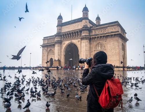 A European tourist girl exploring Mumbai's Gateway of India near Taj Hotel with pigeon's flying around.