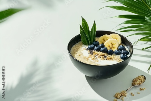 Delicious Oatmeal Bowl Topped With Fresh Bananas and Blueberries in Morning L...