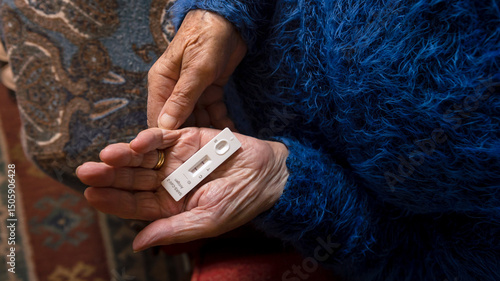 Close-up of old woman hand holding a positive test device for Covid19.