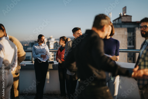 Fotografía A group of multiracial business people engage in a creative brainstorming session on a high-rise rooftop at sunset, fostering collaboration and innovation in a relaxed outdoor setting