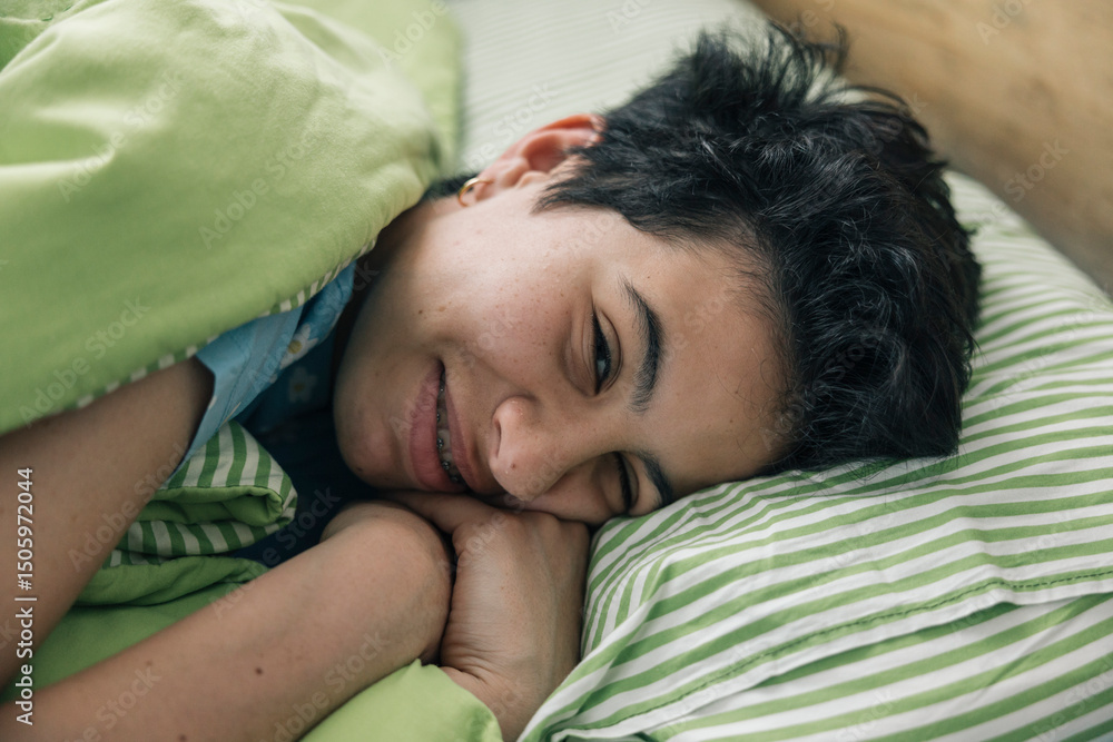Obraz premium Teenager girl waking up and smiling in her bed in the morning
