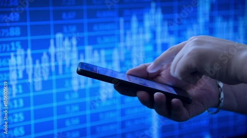Hands using a smart phone displaying financial charts, against a vibrant blue stock market background. Concept of trading. Slow Motion Effect.
