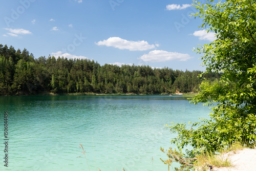 turquoise water lake surrounded by pine trees, view into the distance.It's a beautiful summer day.background, a place to copy