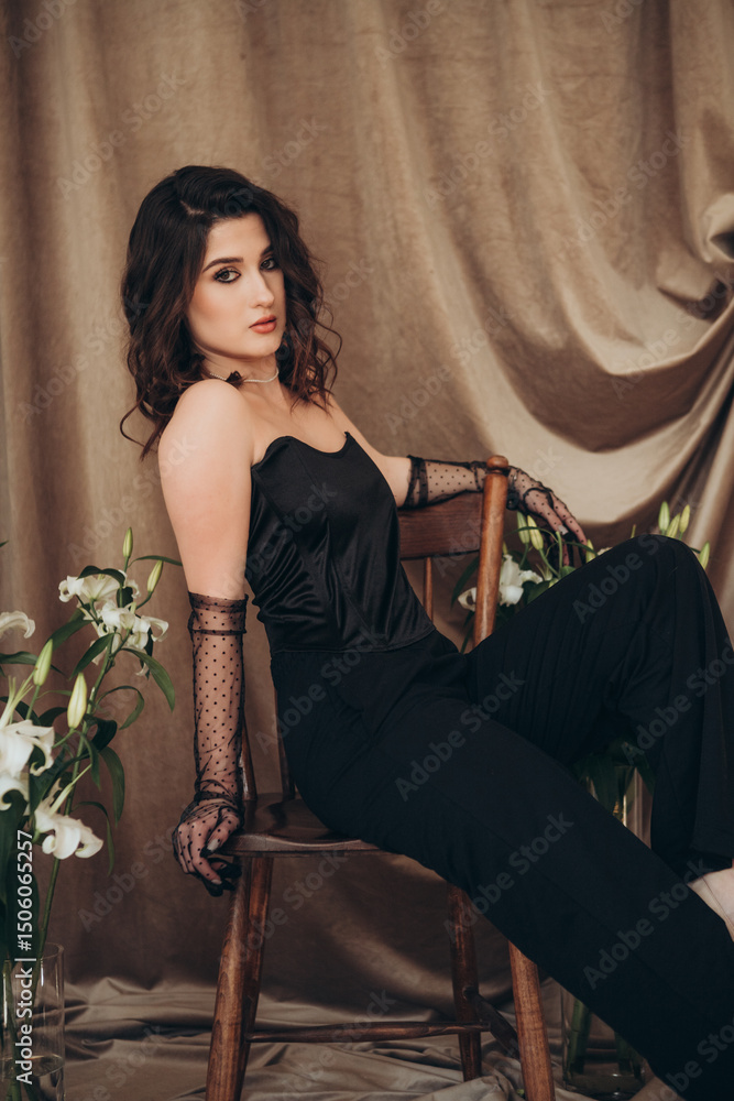 Obraz premium Confident woman in black sitting sideways on chair