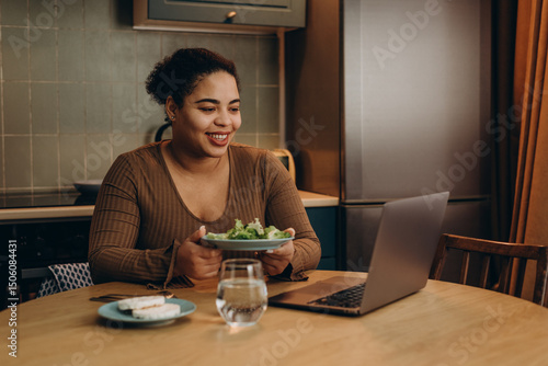 Fotografía Mixed race lady shows plate with lettuce explaining eating disorder at online ap