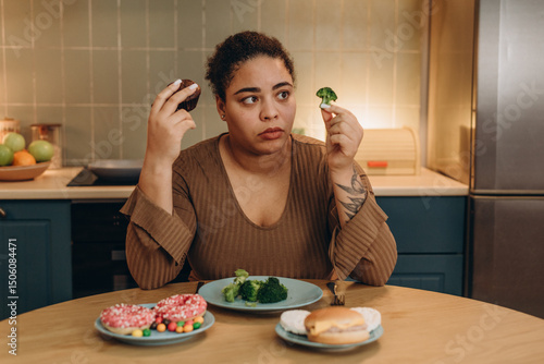 African American woman doubts choice of meal, eating disorder concept