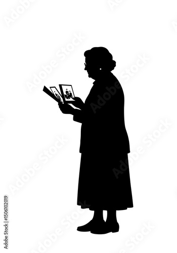 Elderly woman reading photo album while standing in silhouette  