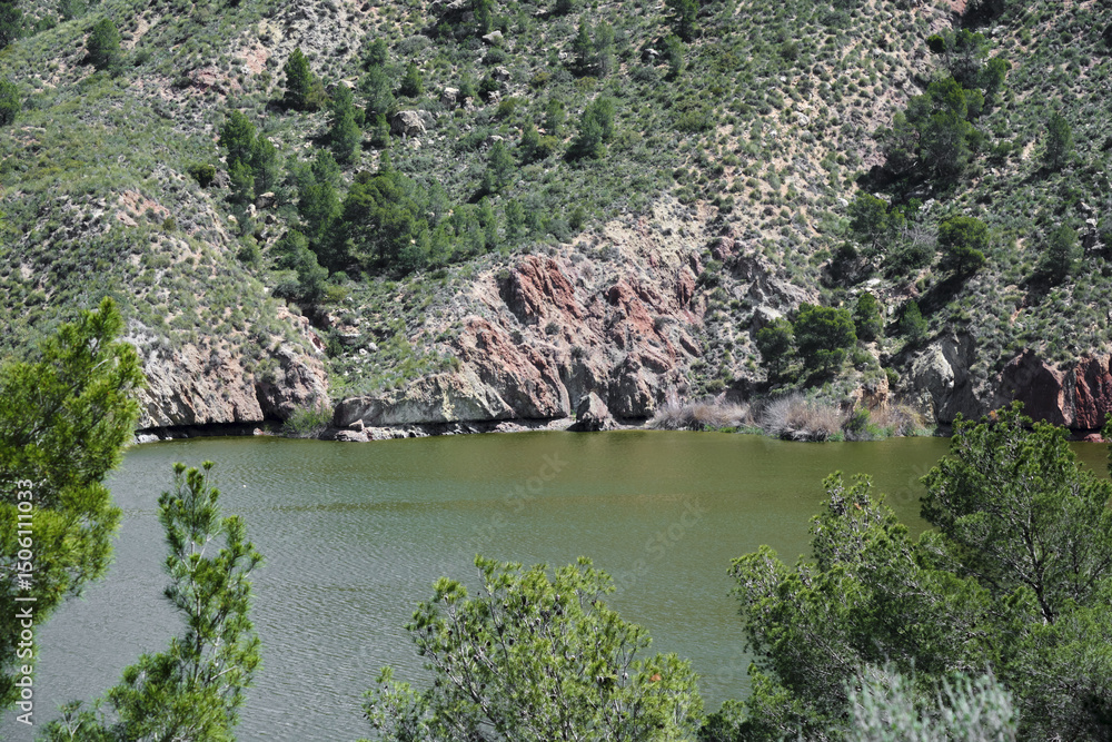Fototapeta premium Serene rocky lakeside with lush greenery and tranquil waters