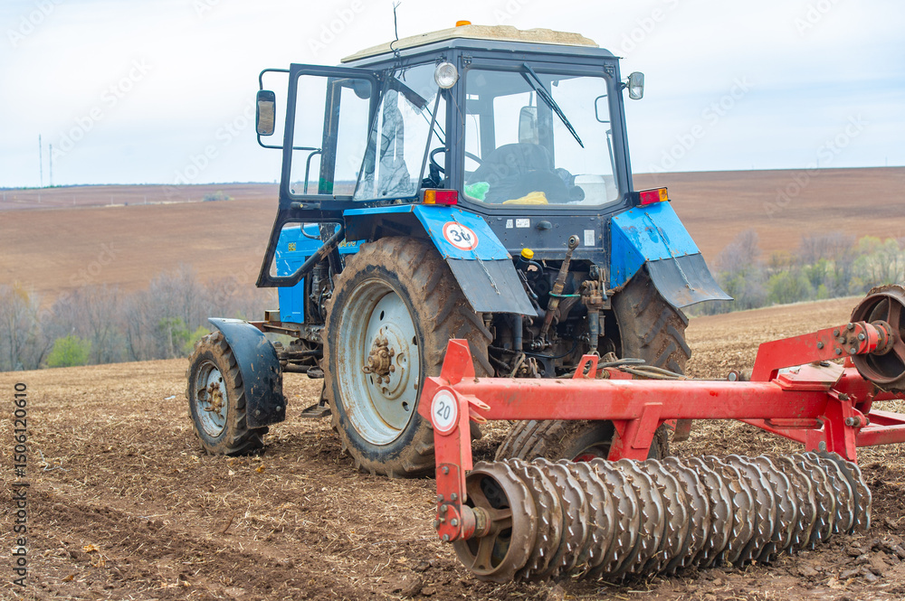 Obraz premium Unleashing the Power of Precision Marvel at the skillful maneuvers of this little blue tractor as it carefully plows the field, paving the way for a bountiful harvest. Agricultural Excellence