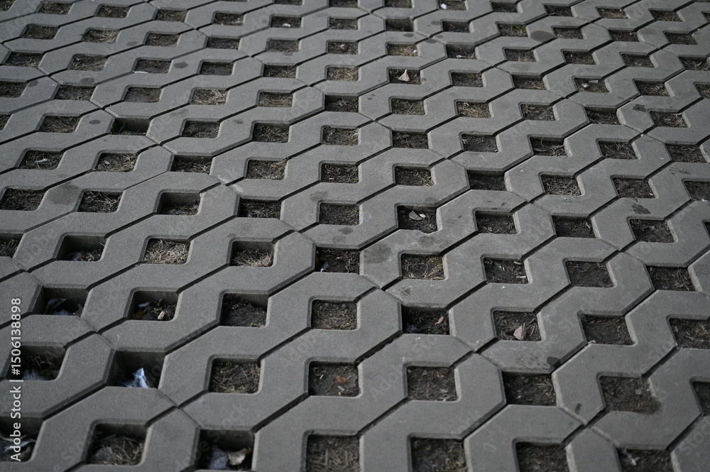 Obraz premium Background texture of square tiles made of gray natural stone. Concrete street covering of road, geometric paving pattern, green lawn and eco parking, green parking, sustainable development city 