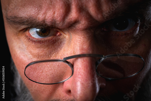 Funny close-up portrait of a quirky bald man with a long gray beard and eyeglasses, making a silly face. Concept of eccentricity, humor, and expressive personality.
