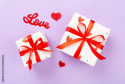 Festive gift boxes with red hearts on color background, top view