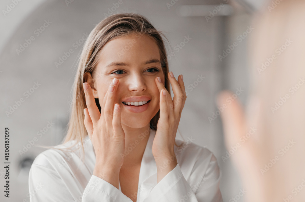 Pretty lady making face-lifting massage in bathroom, looking at mirror and smiling, beautiful caucasian woman using moisturizing face cream after shower, free space Pretty lady making face-lifting massage in bathroom, looking at mirror and smiling, beautiful caucasian woman using moisturizing face cream after shower, free space