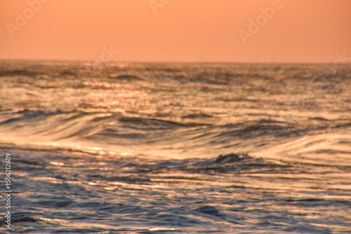 Wave sea beach and sunset sky abstract background. Nature and summer concept. Summer background, warm beach view with sunset, calm waves and sun rays reflecting on sea surface. vacation concept.