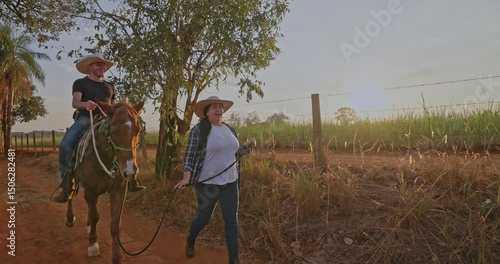 Wallpaper Mural Young man having fun learning to ride a horse on a farm visit being guided by his friend. Torontodigital.ca