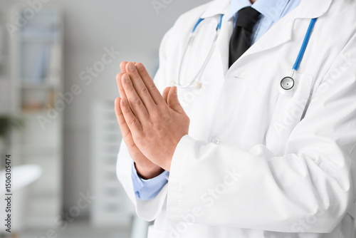 Male doctor praying in clin...