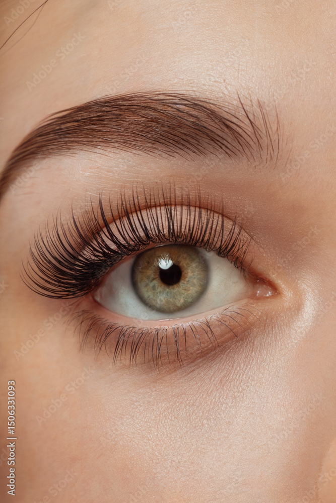 Fototapeta premium A close-up macro photograph of a light brown-green eye with dramatic false eyelashes. 
