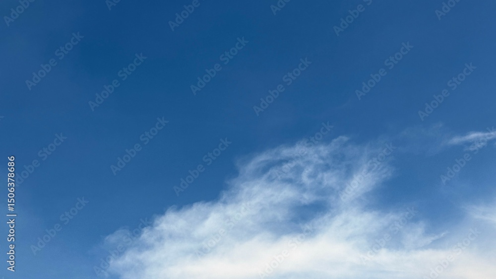 Fototapeta premium White cloud edges softly meet the crisp blue horizon in the clear sky