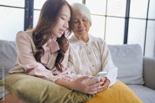 Young Asian Woman Helping Grandmother For Using new app on smartphone.