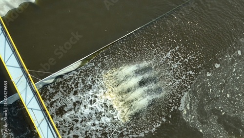 A paddlewheel aerator churns murky wastewater, boosting oxygenation to support microbial breakdown of contaminants in industrial treatment ponds.
