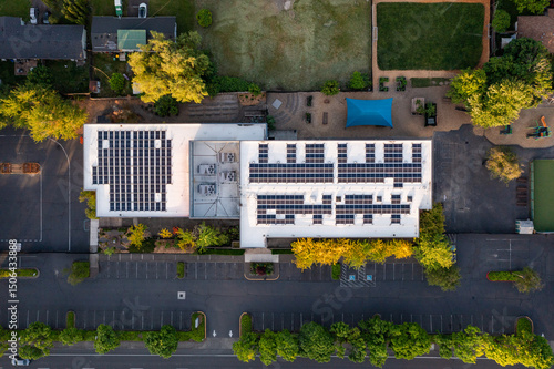 Aerial drone picture of a modern educational building in Beaverton, Oregon, showing large rooftop solar panels and HVAC units. Captured at sunset, emphasizing clean energy and sustainable design