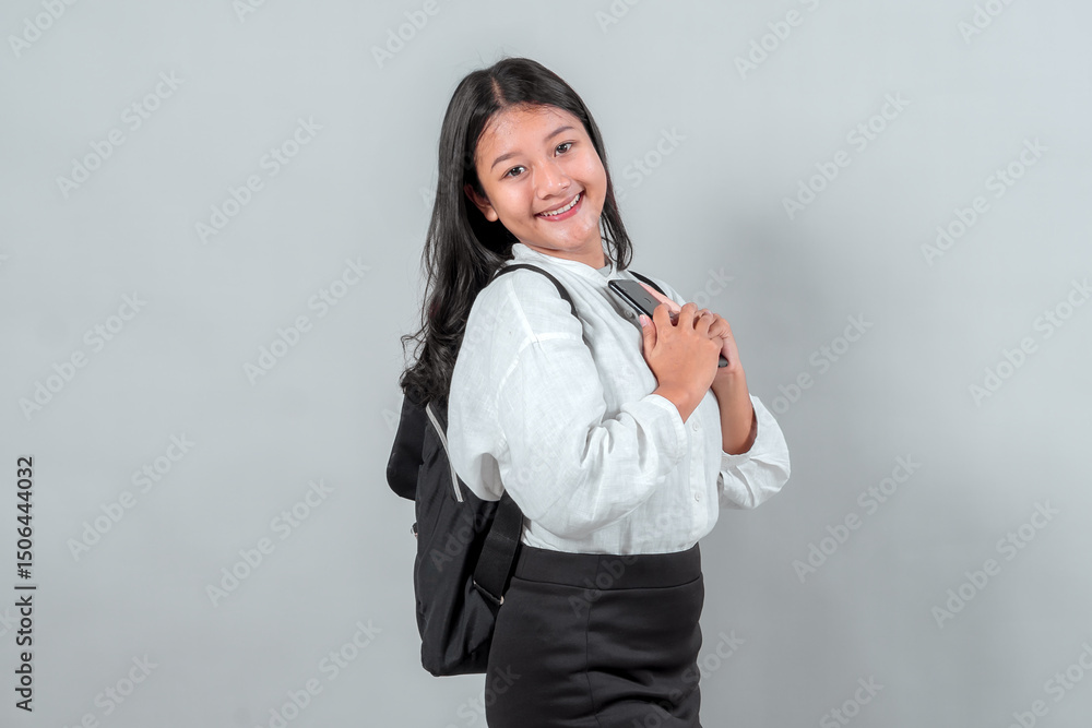 Confident Asian schoolgirl wearing a white blouse and black skirt, carrying a backpack and holding a smartphone to her chest, smiling brightly. Perfect for back to school concepts. Confident Asian schoolgirl wearing a white blouse and black skirt, carrying a backpack and holding a smartphone to her chest, smiling brightly. Perfect for back to school concepts.