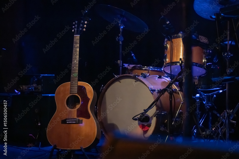Fototapeta premium A Guitar and Drum Set on a Dark Moody Stage at a Venue for a Local Live Music Concert