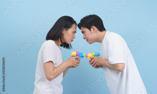 Playful standoff between two friends with water guns against a soft blue background
