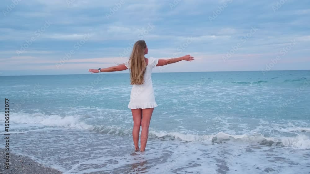 Blonde woman enjoying ocean waves during beautiful twilight. Feeling of freedom Blonde woman enjoying ocean waves during beautiful twilight. Feeling of freedom