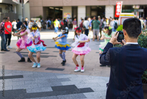 Businessman taking a photo of a Japanese girl group performing a routine outside Akihabara station in Tokyo.