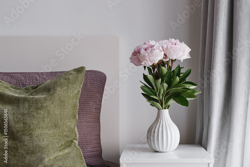 Minimal Bedroom Interior Decor with Fresh Pink Peony Flowers in a White Ceramic Vase and Cushions