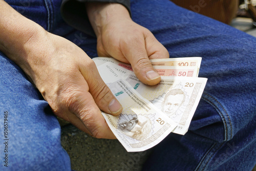 Fotografie A tourist sits on a bench and counts money after receiving it at a currency exch