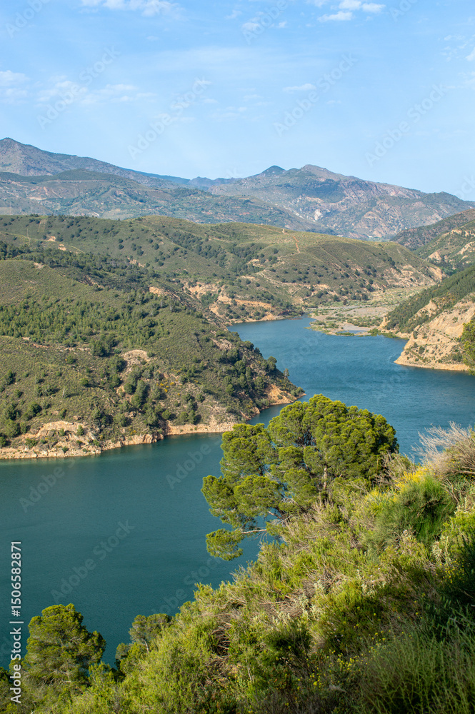 Fototapeta premium Rules Reservoir on the Guadalfeo River is a vital water body nestled among striking mountainous terrain, offering picturesque views and regional significance in Granada, Spain