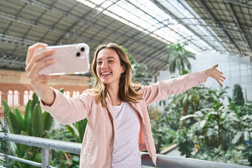 Young woman taking selfie in atocha station showing tropical garden
