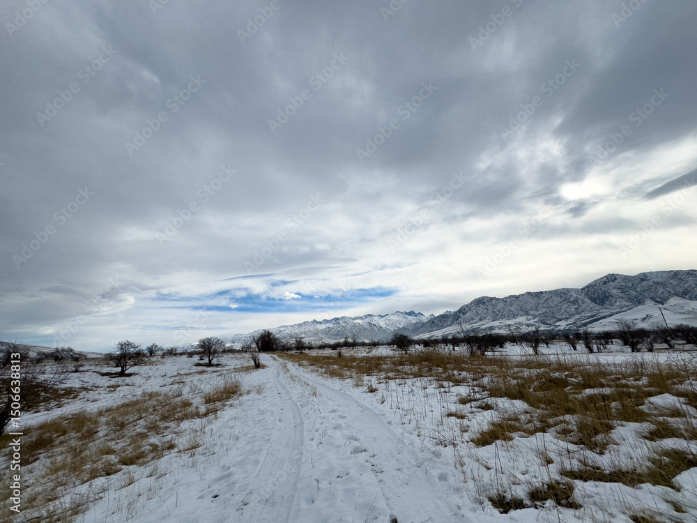 Snow covered mountains in Kyrgyzstan under cloudy winter sky peaceful rural landscape Snow covered mountains in Kyrgyzstan under cloudy winter sky peaceful rural landscape