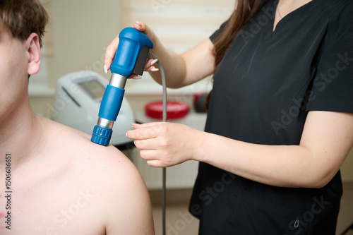 Wallpaper Mural Physical therapy of shoulder with acoustic shock waves. Close up view of doctor performing shock wave therapy procedure on back. Female holding pneumatic shock wave therapy machine for pain relief. Torontodigital.ca