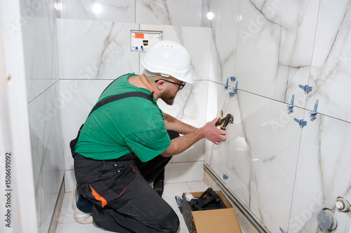 Plumber installing a handheld bidet sprayer. Plumbing for wall mixer. Wall mounted tap or shower mixer. Handheld bidet spray in toilet. Hygienic shower with mixer. Best drain snaking services.