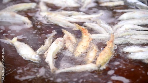 Delicious fresh fish fried in large frying pan, cooking outdoors, smelt fish