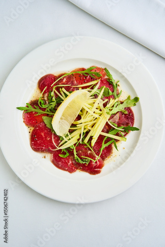 Delicious Beef Carpaccio Topped With Fresh Herbs and Citrus Served on a White Plate at a Cozy Restaurant