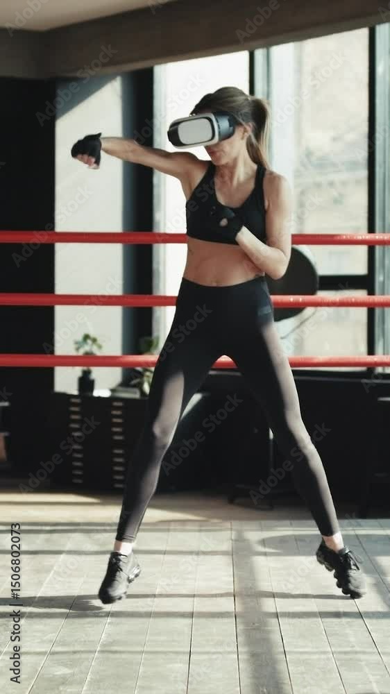 Vertical Video of Athletic woman in vr headset boxing indoor. Female in sportswear using virtual reality headset. Technology. Woman boxing in VR 360 headset training for kicking in virtual reality Vertical Video of Athletic woman in vr headset boxing indoor. Female in sportswear using virtual reality headset. Technology. Woman boxing in VR 360 headset training for kicking in virtual reality