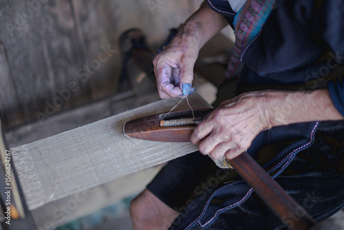 Close-up of elderly hands weaving fabric on a traditional wooden loom