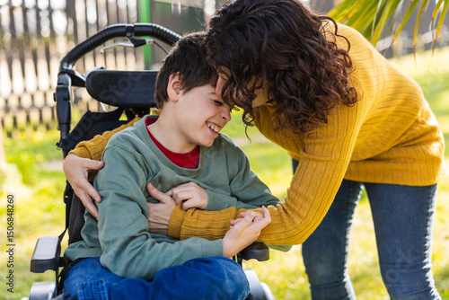 Mother embracing son with disability in wheelchair in park, cerebral palsy awareness