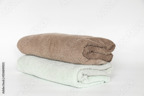 Light blue and brown towels, rolled up on white background, home textile item
