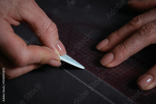 Detailed close-up photograph showing hands guiding fabric through an industrial sewing machine. The image captures the precision and craftsmanship involved in textile production and tailoring. Ideal f