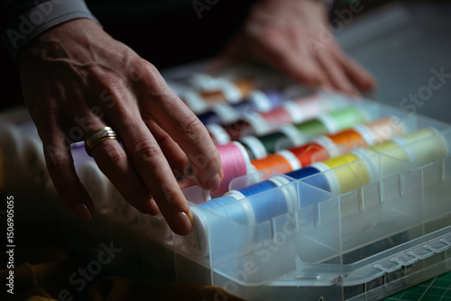 Detailed close-up photograph showing hands guiding fabric through an industrial sewing machine. The image captures the precision and craftsmanship involved in textile production and tailoring. Ideal f